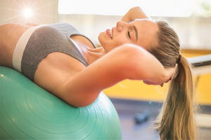 בחורה מבצעת כפיפות בטן על כדור ירוק