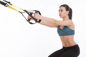 בחורה חטובה מדגימה סקוואט עם TRX