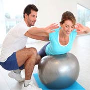 מאמן עוזר ללקוחה בתרגיל עם כדור